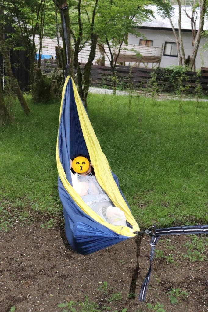MOSS十里木キャンプリゾートの敷地内で、青いハンモックにすっぽり入ってリラックスする子どもの様子