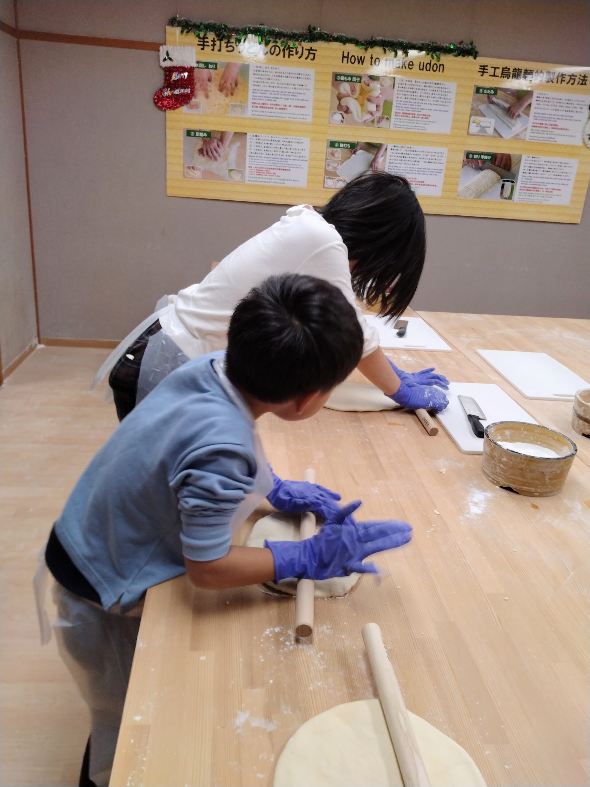 手打ちうどん体験で生地を麺棒で伸ばす子どもたち