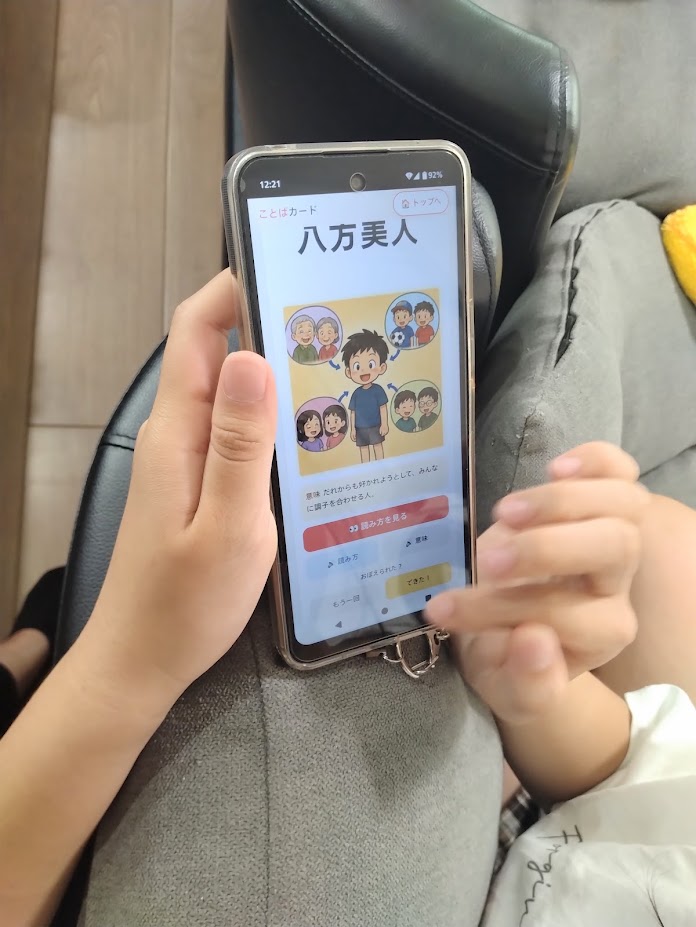 スマホで三字熟語・四字熟語学習アプリを使う姉さんの手元